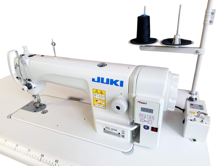 Stebnówka JUKI DDL-8700H, jednoigłowa maszyna do szycia z silnikiem Direct Drive. Widoczna biała obudowa, cyfrowy panel sterujący z wyświetlaczem, stopka do szycia oraz dwa szpulki z czarną nicią na górze.