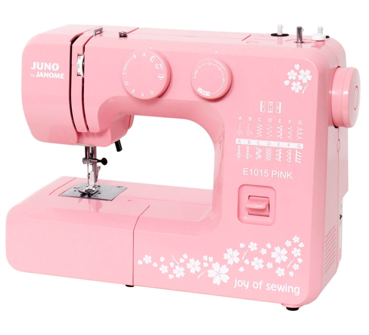 Maszyna do szycia Janome JUNO E1015 w kolorze różowym, z białymi dekoracjami kwiatowymi. Widoczne pokrętła do regulacji, przyciski oraz stół z igłą. Produkt ustawiony frontalnie, z otwartym mechanizmem szyjącym, prezentujący funkcje i design.