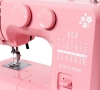 Maszyna do szycia Janome JUNO E1015 PINK w kolorze różowym. Widoczne pokrętła do ustawiania ściegów oraz instrukcje na obudowie. Na froncie znajduje się logo E1015 PINK oraz wzory ściegów. Ujęcie z boku, ukazujące detale i funkcje maszyny.