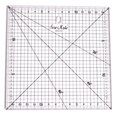 Linijka do patchworku i quiltingu o wymiarach 150x150 mm, przezroczysta z siatką. Widoczne podziałki oraz kąty 30°, 45° i 60°. Ułożona płasko, z otworem do zawieszenia. Jasne tło podkreśla detale i oznaczenia.