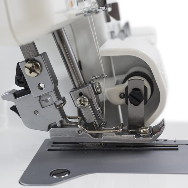 Zbliżenie na mechanizm owerloka JUKI MO-644D, 4-nitkowego. Widoczne są igły, prowadnik nici oraz stopka, z metalowymi elementami i szarym podkładem. Produkt w pozycji stojącej, na białym tle, z wyraźnymi detalami konstrukcyjnymi.