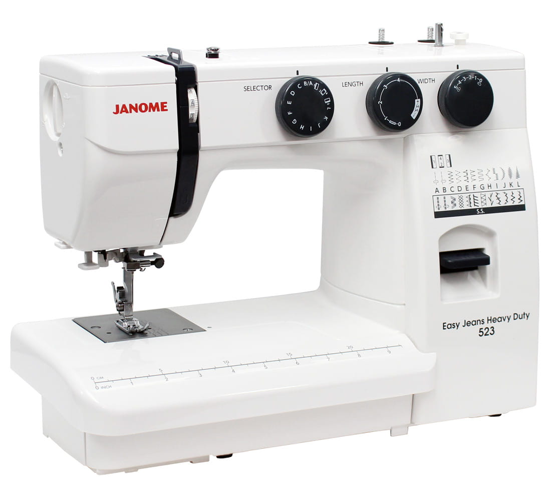 Maszyna do szycia Janome HD 523 EASY JEANS w kolorze białym, z pokrętłami do wyboru ściegów, długości i szerokości. Widoczny stół do szycia z linią pomiarową oraz symbolami różnych ściegów. Stojąca, z czytelnymi oznaczeniami na obudowie.